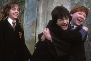 Harry, Ron and Hermione are hugging and laughing
