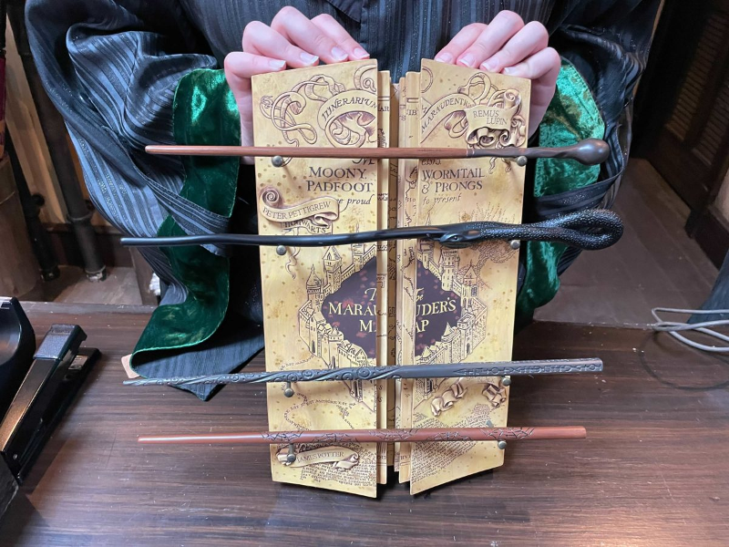 The Marauder's Map Wand Collection at Universal Orlando Resort is pictured in a photograph from WDW News Today. It features the wands of the four Marauders on a decorative Marauder's Map stand.