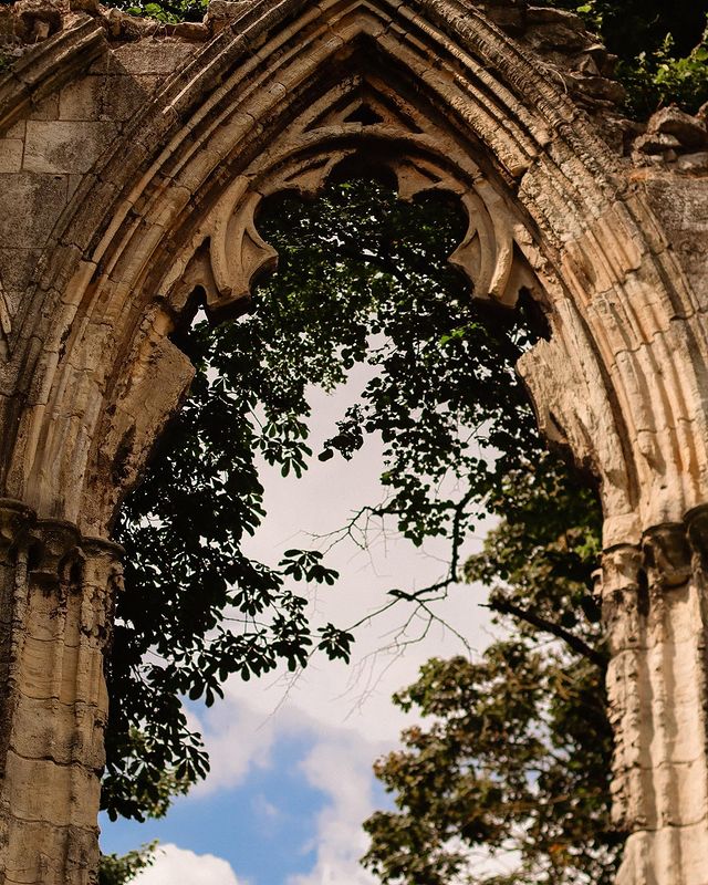 The sky shines through an old archway that looks like part of Hogwarts Castle