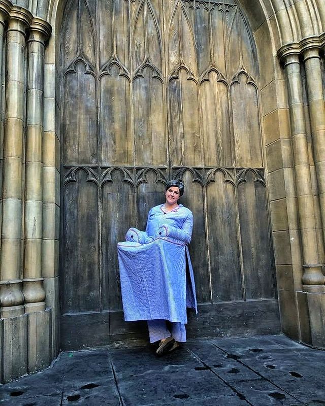 A Harry Potter fan stands dressed as Slughorn, partially disguised as an armchair