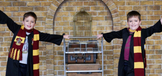 Two children are photographed posing on either side of the Platform 9 3/4 trolley at Edinburgh Waverley on October 16, 2021.