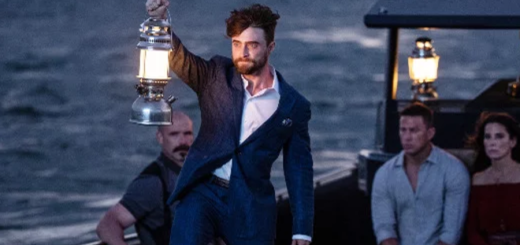 In a still from "The Lost City" from Paramount Pictures, Daniel Radcliffe can be seen in character as Fairfax. He is holding a lantern at the bow of a boat as Sandra Bullock and Channing Tatum's characters, seated on the boat behind him, look on.