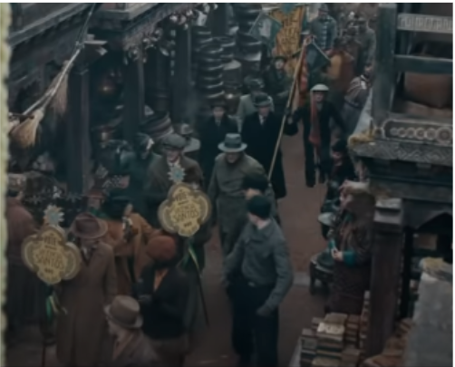 A still from the Fantastic Beasts: Secrets of Dumbledore showing Aberforth Dumbledore moving through a crowd in Bhutan