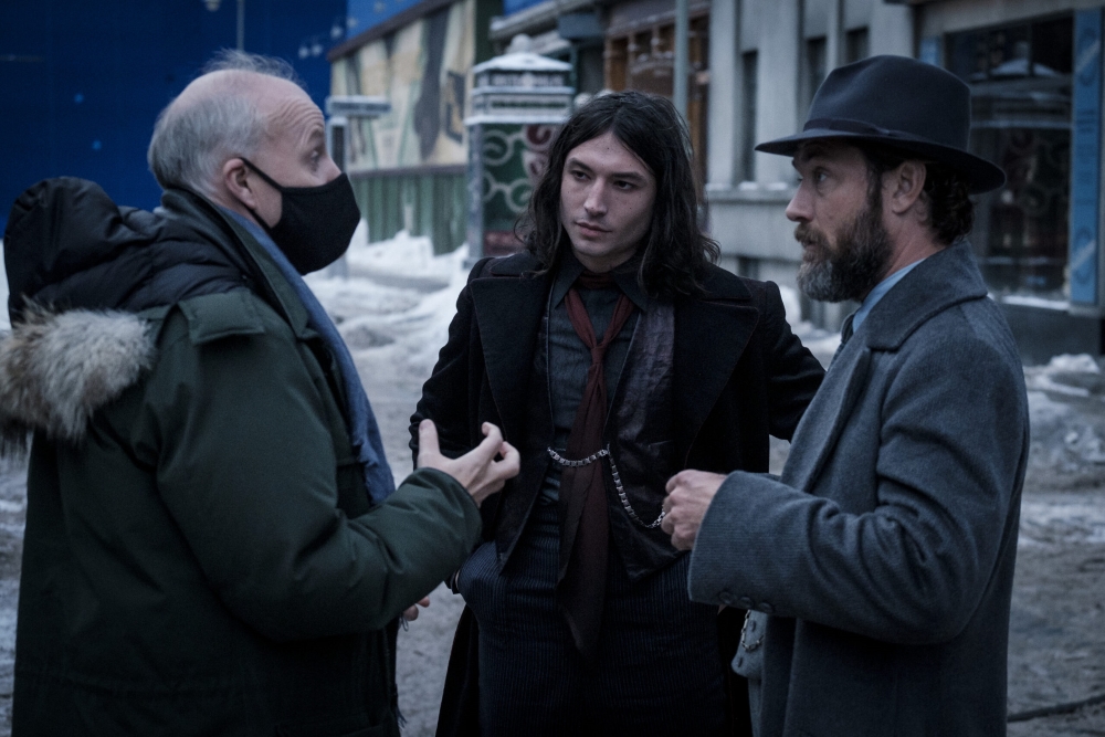Director David Yates is shown conversing with actors Ezra Miller (Credence Barebone) and Jude Law (Albus Dumbledore) on the set of “Fantastic Beasts: The Secrets of Dumbledore.”