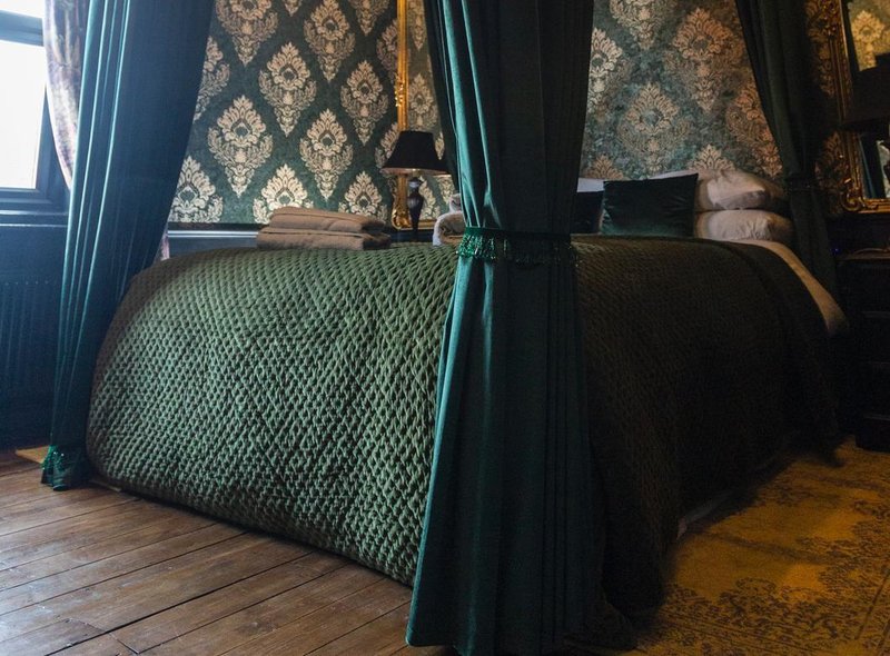 A bedroom in the Yorkshire "Harry Potter"-themed Airbnb includes green wallpaper and bedding.