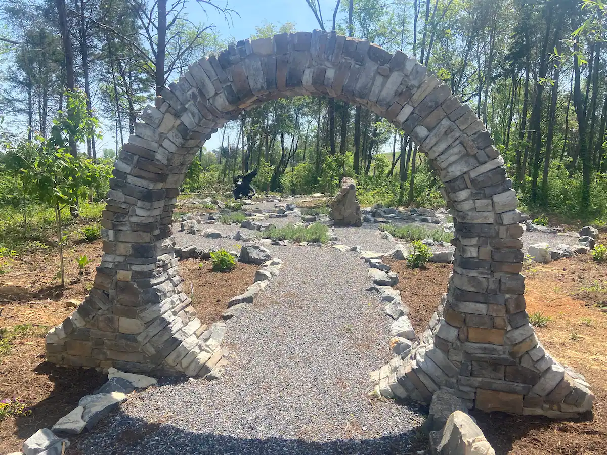 A stone archway is located in the forest near the Wizard’s Trolley.