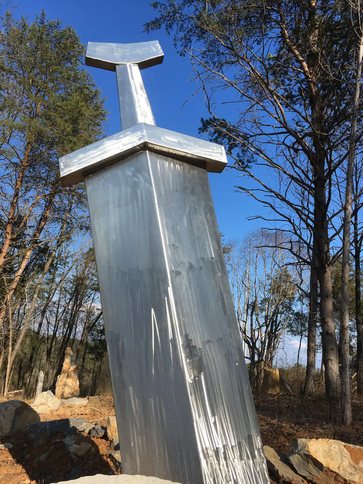 A giant sword statue is located in the forest near the Wizard’s Trolley.