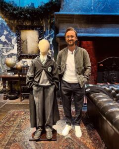 Tom Felton standing beside his old Draco Malfoy costume