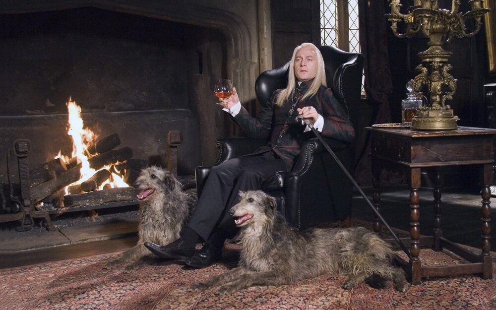 Lucius Malfoy sitting at home with two elegant canines