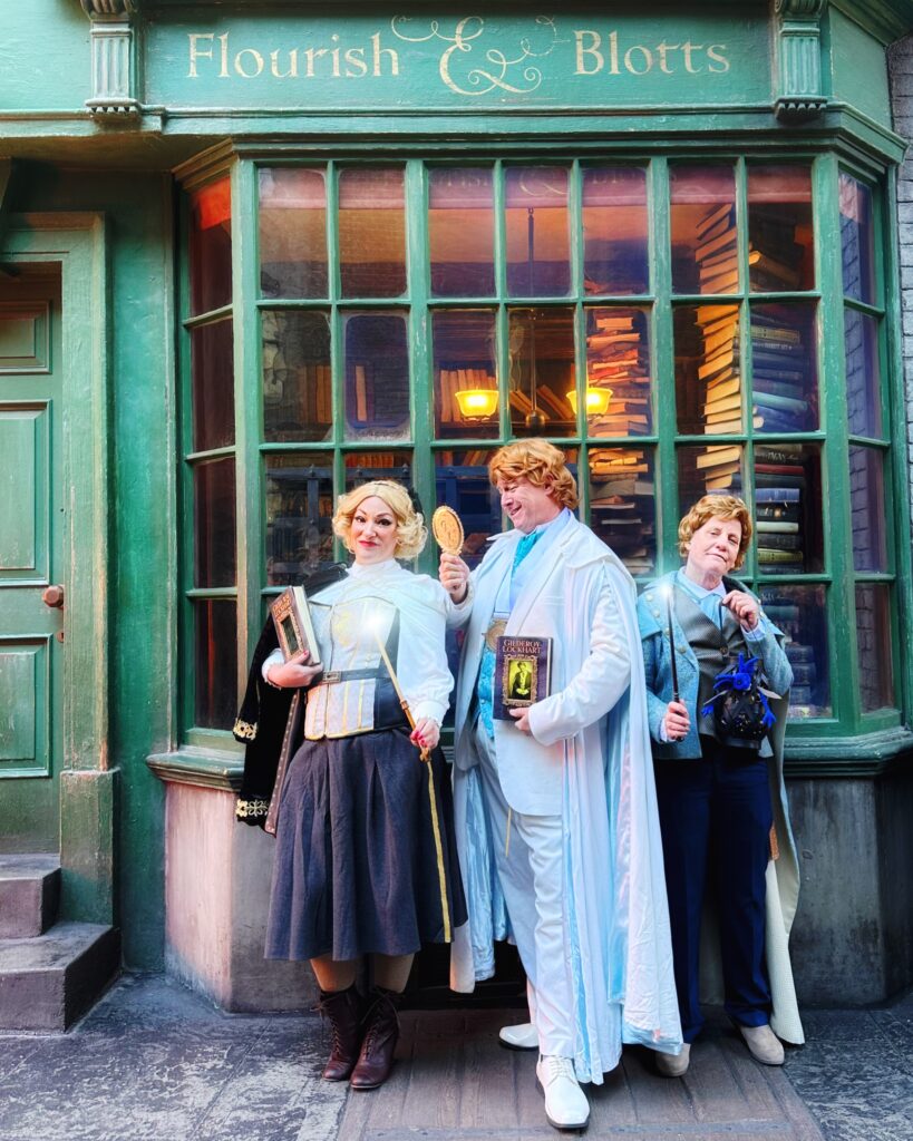 Three Harry Potter fans stand in Diagon Alley dressed as three versions of Gilderoy Lockhart