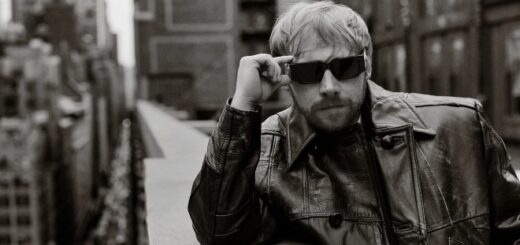 Rupert Grint poses in sunglasses on a balcony.