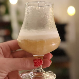 Someone holds a Butterbeer cocktail aloft