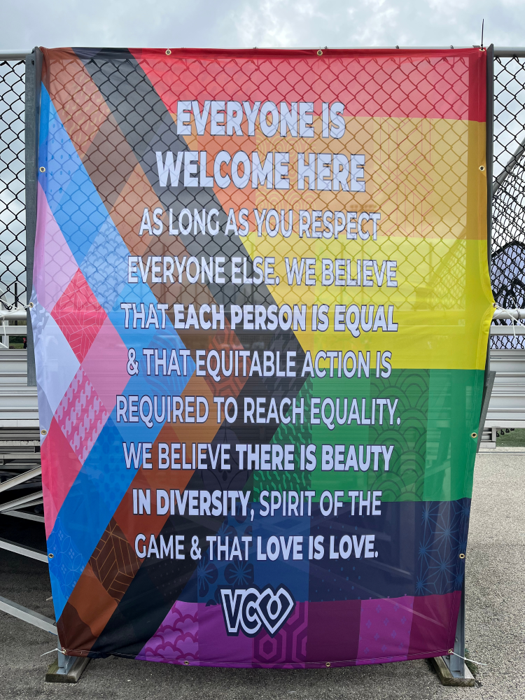 A banner featuring white text on a Progress Pride Flag background welcomes those present at USQ Cup 2023.