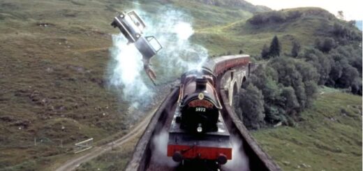 A movie still from "Harry Potter and the Chamber of Secrets" where Harry dangles from the flying Ford Anglia over the Hogwarts Express.