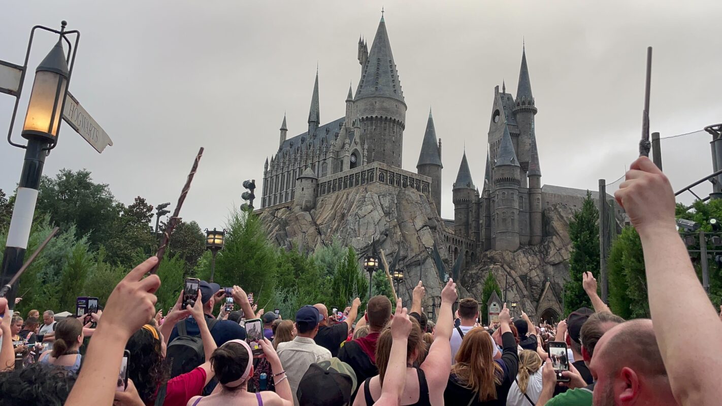 fans raise wands in front of Hogwarts Castle