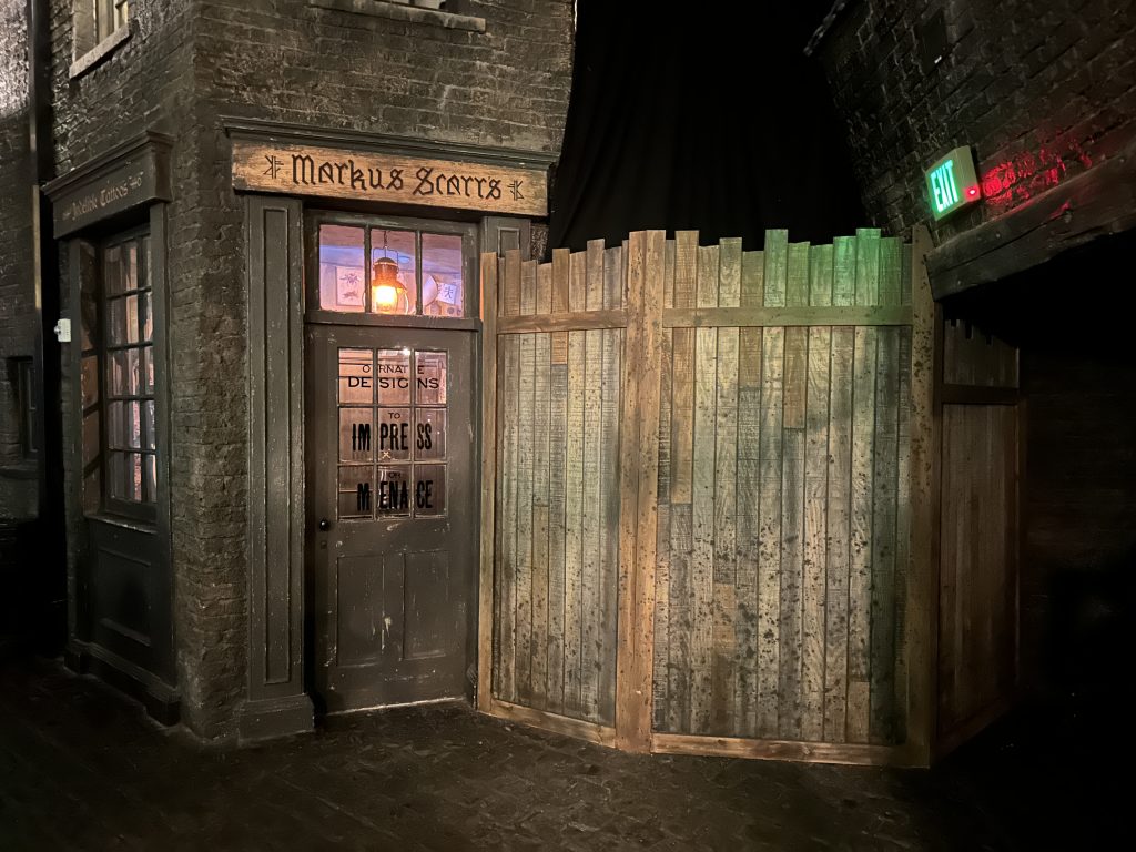 A work wall stands beside "Markus Scarrs" wizarding tattoo parlor in Knockturn Alley.