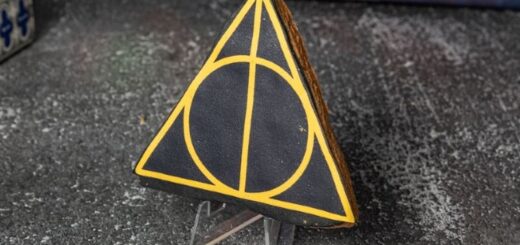 A black triangular cookie emblazoned with the Deathly Hallows sign in gold sits on display.