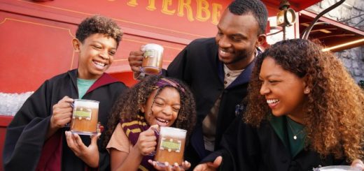 A smiling family in Hogwarts robes enjoys mugs of Butterbeer.